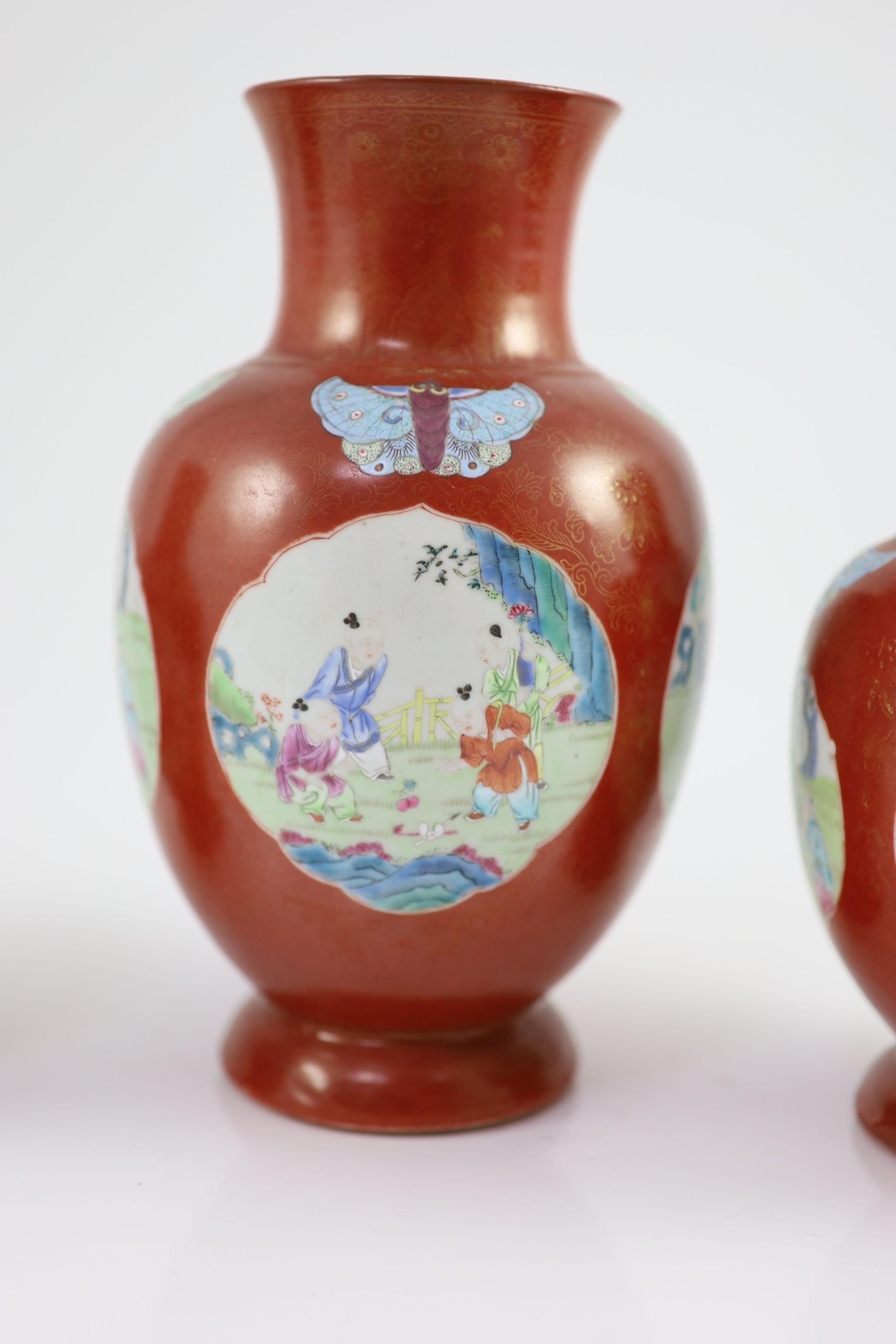 A set of three Chinese coral ground ‘boys’ vases, Jiaqing period (1796-1820), 19.5 and 23.5cm high